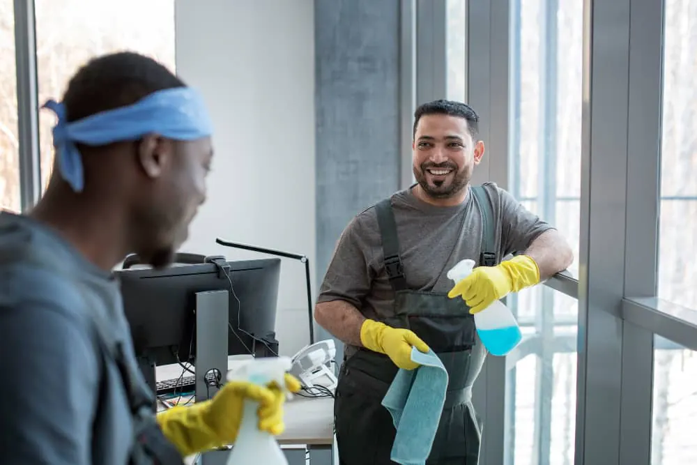 Cleaners disinfecting desks and monitors in an office